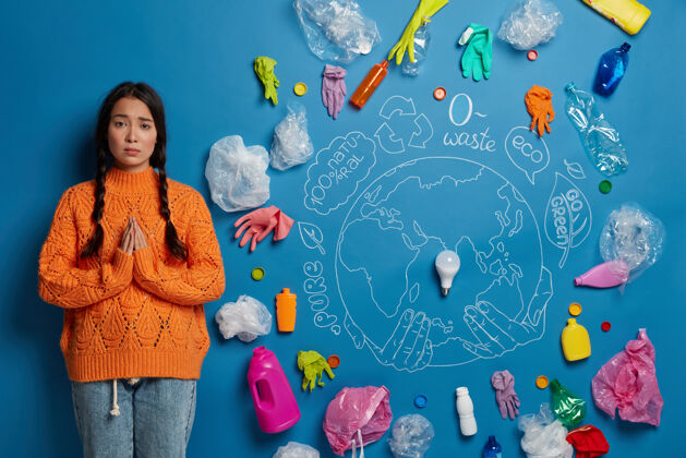 全球生态和土地保护概念悲伤的亚洲妇女站在祈祷的姿势 周围的塑料垃圾 乞求帮助清洁地球 穿着随意垃圾污染祈祷