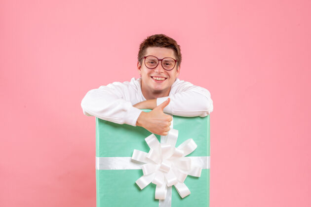 礼物正面图：身穿白色衬衫的年轻男性 粉色背景上带着微笑的礼物微笑睡衣粉色