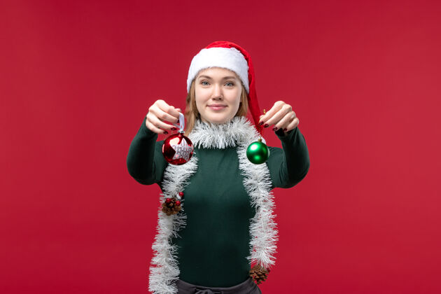 乐趣正面图红色背景上手持圣诞树玩具的年轻女性风景圣诞帽子