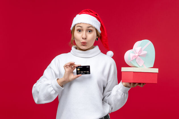帽子正面是一位年轻女士 她拿着礼物和红色背景上的银行卡礼物视图脸