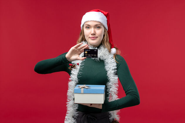 正面正面图是一位年轻女士 带着礼物和红色背景的银行卡成人年轻女子肖像