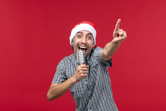 圣诞正面图：年轻男性在红色背景上用麦克风唱歌人红色男人