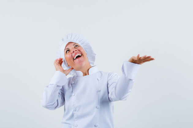 时尚女厨师摆出一副像在打电话一样的姿势 一边摊开手掌 穿着白色制服 看上去很健谈看起来交谈电话