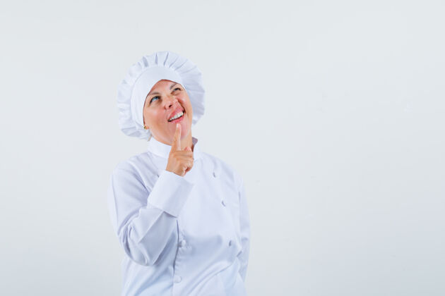 时尚身着白色制服的女厨师展示了一分钟的手势 并期待沉思的文字空间化妆制服粉色