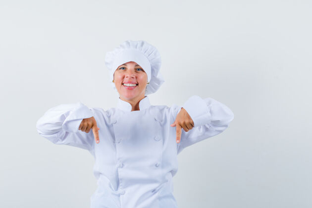 护理穿着白色厨师制服的金发女人用食指指着下面 看起来很漂亮制服健康时尚
