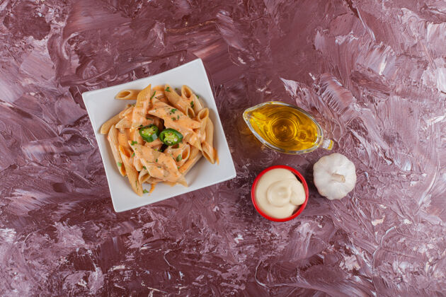 午餐淡桌上放着蛋黄酱和新鲜大蒜的潘恩意大利面烹饪一餐装饰
