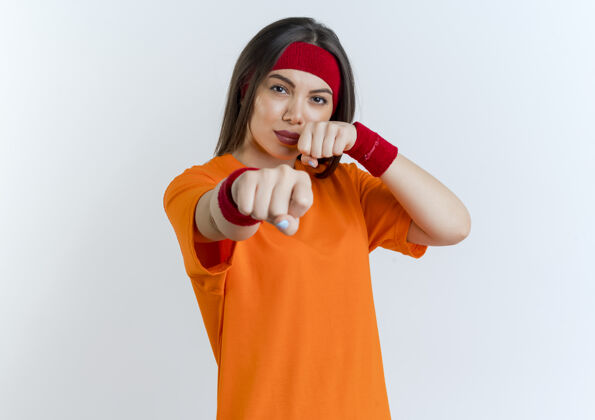 长相自信的年轻运动女性戴着头带和腕带做拳击姿势隔离在白色墙壁与复制空间头带女子腕带