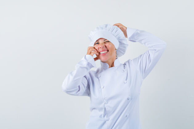 乐趣一位身穿白色制服的女厨师手把手放在头上和脸颊上 看上去很漂亮学生休闲女士
