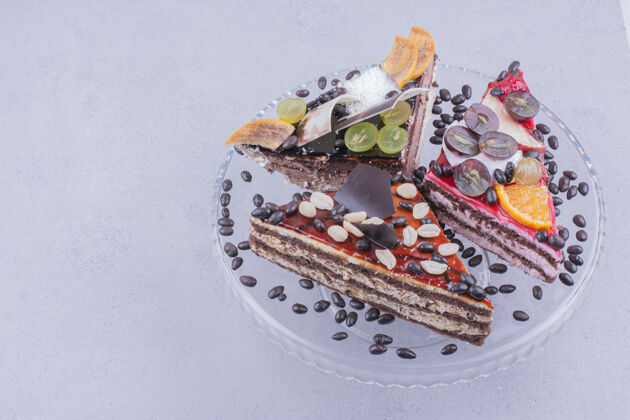 樱桃三角形状的巧克力蛋糕片与坚果和水果放在一个玻璃盘子里与豆子奶油甘纳切甜点