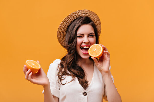 波浪发一幅调皮女孩的肖像 波浪形头发咬着橙色戴草帽的女士在橙色背景上摆姿势女人卷发橙色