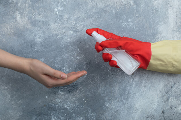 人把喷洒乙醇的防护手套交给女人防护钢铁手套