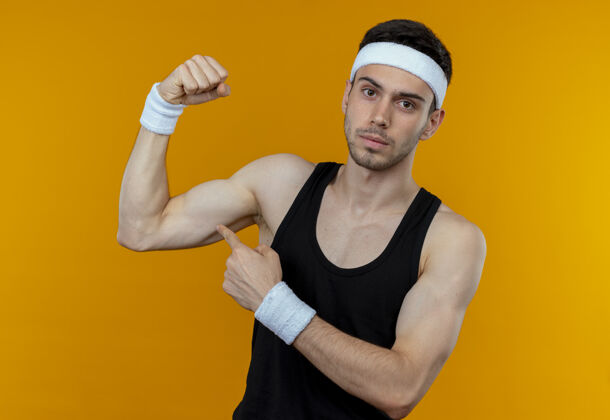 严肃戴着头巾的年轻运动型男子举起拳头 展现出二头肌严肃自信的表情展示自信头带