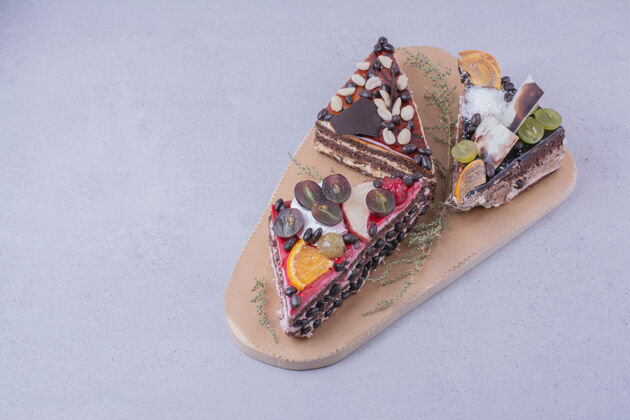 香草在木板上放巧克力和水果的三角形蛋糕片奶油美味可可