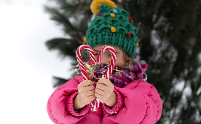 糖果快乐的孩子 在圣诞树下放着一根大糖果棒寒假概念女孩雪乐趣