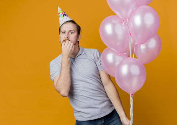 帽子戴着节日帽的年轻人举着一堆气球庆祝生日 对橙色感到惊讶惊喜气球橙色