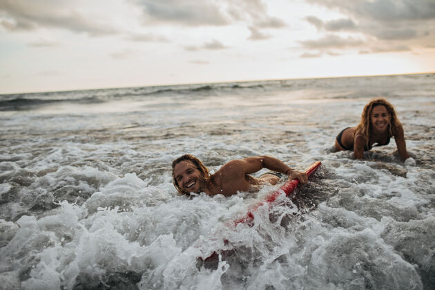 男性女人和她的男朋友在海里冲浪封闭情侣大海