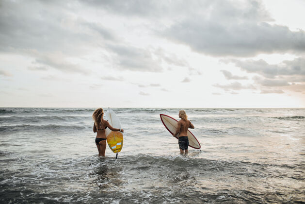成人一对情侣在沙滩上摆姿势去冲浪年轻男人微笑