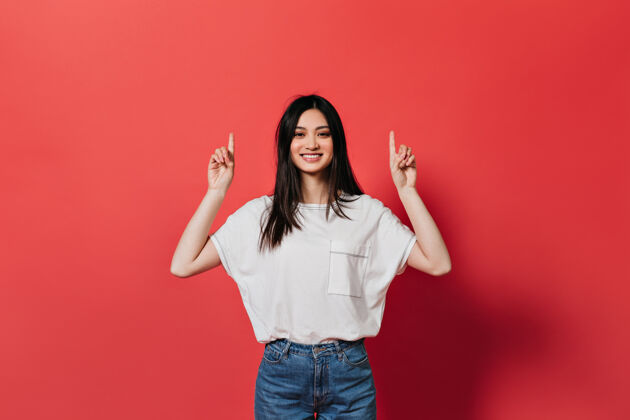金发心情很好的亚洲女人正在竖起手指准备在红墙上放文字女人朋友积极
