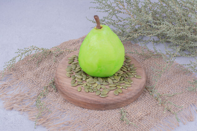 异国情调一个绿色的梨放在木板上 周围有南瓜子热带艺术酸味