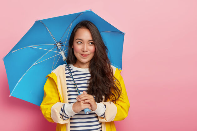 衣服漂亮体贴的女人 深色直发 拿着蓝色雨伞 在凉爽的日子里散步 保护自己不受雨淋思考女性举行