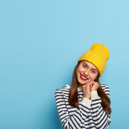 水手容貌开朗的女人仰着头 微笑温柔 双手合十 戴着黄色帽子和条纹水手套头衫黑发人季节