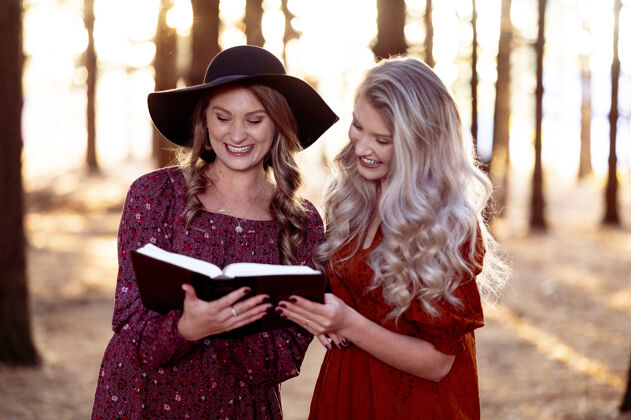 年轻两个年轻女性在森林里和一本书合影的镜头 秋天的心情树选择举行