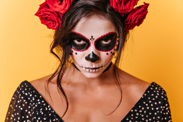 传统一张有着狂欢节面孔艺术的棕色眼睛女人的特写照片墨西哥模特愤怒地看着橙色背景的相机拉丁玫瑰万圣节