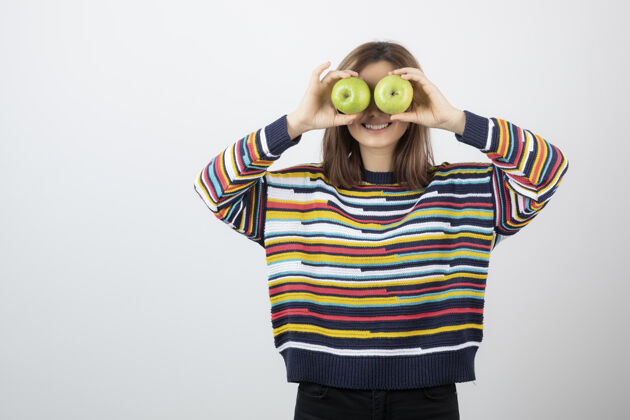 微笑一个穿着休闲装的年轻女人 眼前拿着青苹果水果姿势绿色