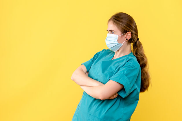 绝育正面图黄色背景上戴无菌口罩的女医生大流行健康病毒人成人女医生