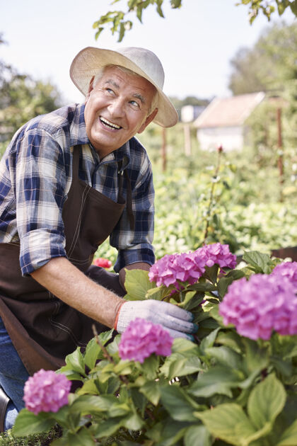 园艺拿着花在地里干活的老人春天自然弯曲