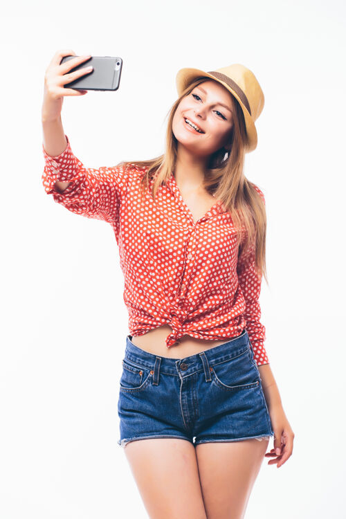 脸快乐调情的年轻女子通过手机拍摄自己的照片 白色背景女性人图片