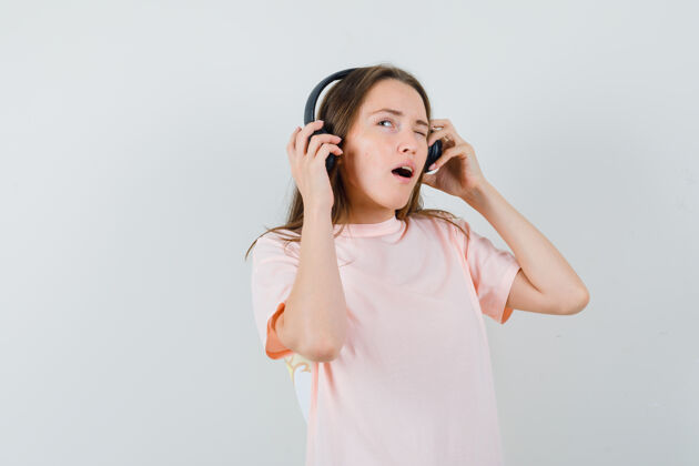 小穿着粉色t恤 戴着耳机欣赏音乐的年轻女孩 神情沉思正视图童年耳机漂亮
