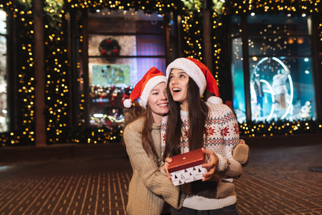 圣诞老人在圣诞夜户外散步时 快乐可爱的年轻朋友们互相拥抱微笑的照片城市夏娃女朋友