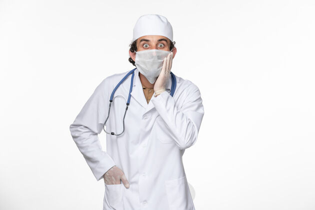 医生正面图男医生穿着医疗服 戴着无菌口罩 以防白色桌面病毒冠状病毒大流行疾病的传播疾病男性正面