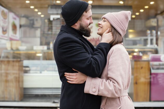 帽子一对年轻的情侣拥抱着看着对方女人侧视男人