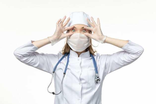 套装正面图身穿白色医疗服 带无菌口罩的女医生因冠状病毒而睁开眼睛看白墙病冠状病毒-大流行性疾病医学冠状病毒预防女性