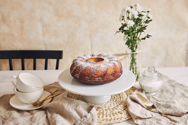 件美丽的镜头美味的环蛋糕放在一个白色的盘子和一个白色的花靠近它粉末面包房糕点