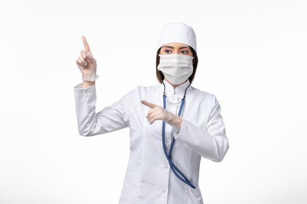 套装正面图女医生身穿白色无菌医疗服 带口罩 因白墙上冠状病毒病大流行疾病冠状病毒大流行冠状病毒正面