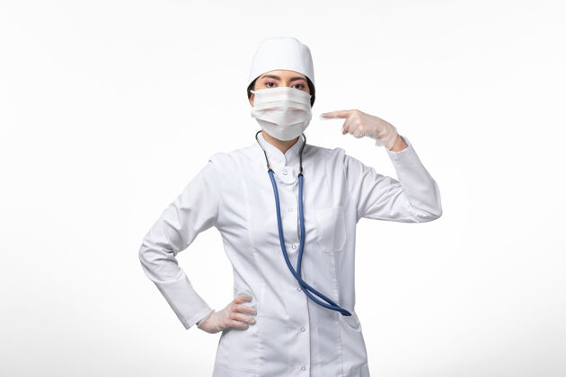 男人正面图：女医生穿着白色无菌医疗服 戴着口罩 因为白墙疾病 传染病肖像医学女性