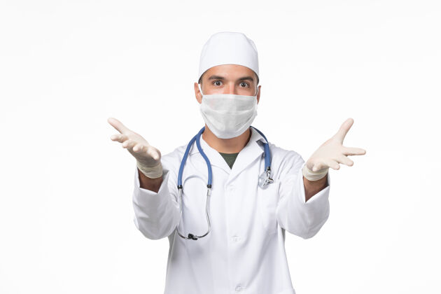 冠状病毒防护正面图：男医生穿着医疗服 戴着防病毒口罩-白色办公桌上的病毒药物-大流行性疾病医疗大流行听诊器