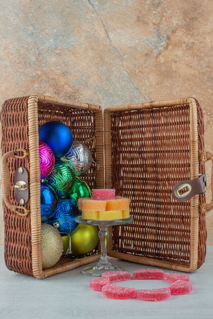 食物打开的手提箱里装满了五颜六色的圣诞球和大理石背景上的果酱高质量的照片五颜六色可口圣诞球