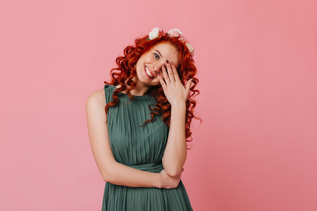 帽子迷人的红发姑娘 头上戴着鲜花 笑容甜美 用手捂着脸粉色空间里的绿装淑女画像发型少女花冠