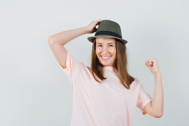 头年轻女性穿着粉色t恤 戴着帽子 手放在头上 看起来很吸引人 正面视图快乐女人年轻