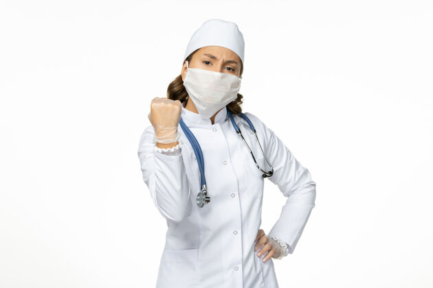 病毒正面图女医生穿着白色医疗服 戴着口罩 由于桌上有冠状病毒 呈浅白色大流行病毒病隔离冠状病毒专业面罩套装
