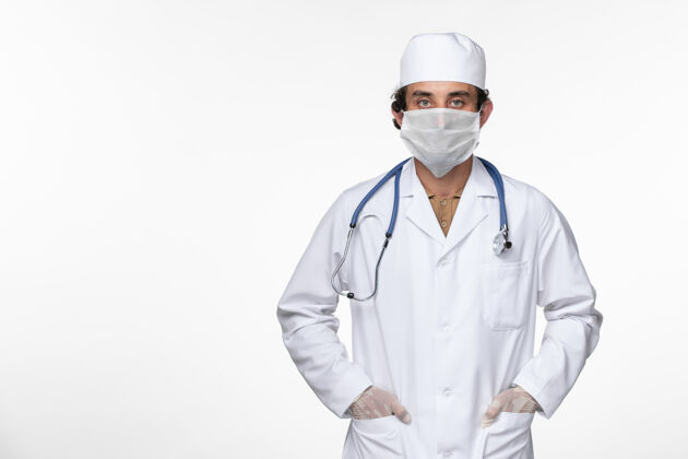大流行正面图身穿医疗服的男医生戴着无菌口罩 以防白色桌上型冠状病毒大流行疾病办公桌视图正面