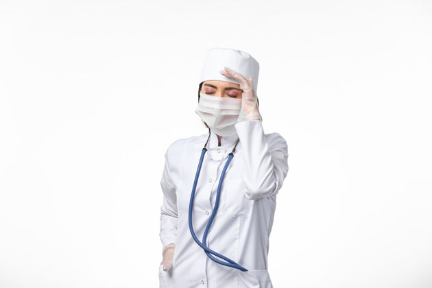药正面图女医生穿着白色医疗服 戴着口罩 因冠状病毒头痛白墙病医学病毒大流行疾病人头痛