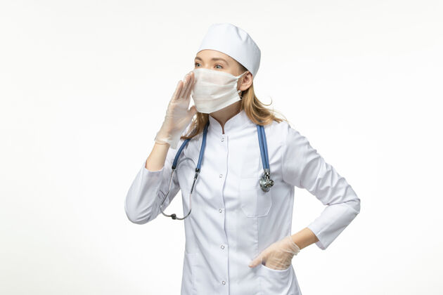 护士正面图女医生穿着医疗服 戴着口罩和手套 因白墙上冠状病毒病大流行健康冠状病毒微笑女性到期