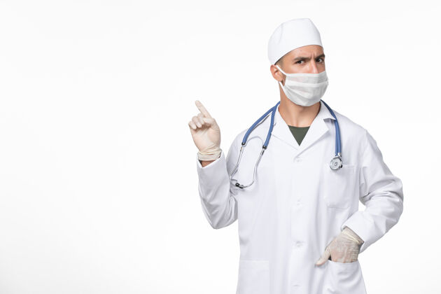 防护正面图：男医生穿着医疗服 戴着口罩 对抗白色墙壁上的冠状病毒病 医学大流行病毒套装专业