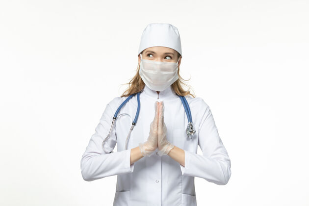穿戴正面图女医生穿着医疗服戴着口罩戴着手套因白色办公桌上冠状病毒大流行冠状病毒帽子肖像冠状病毒