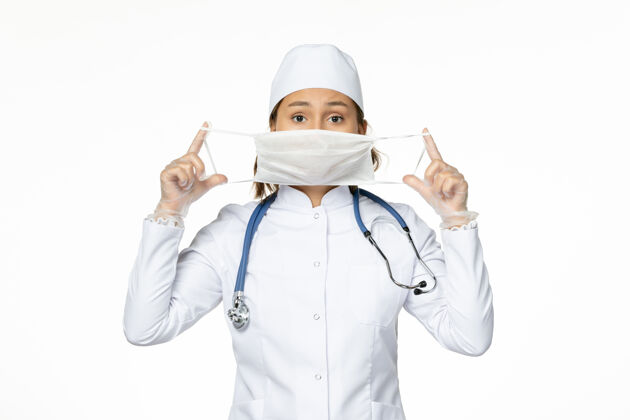 前线正面图女医生穿着白色医疗服 戴着无菌口罩 在白墙上隔离大流行性疾病的药物病毒医务人员大流行套装